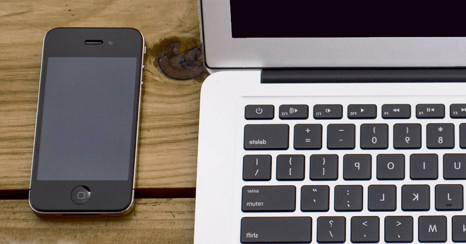 Крупный план iPhone и ноутбука: телефон рядом с открытым ноутбуком на столе