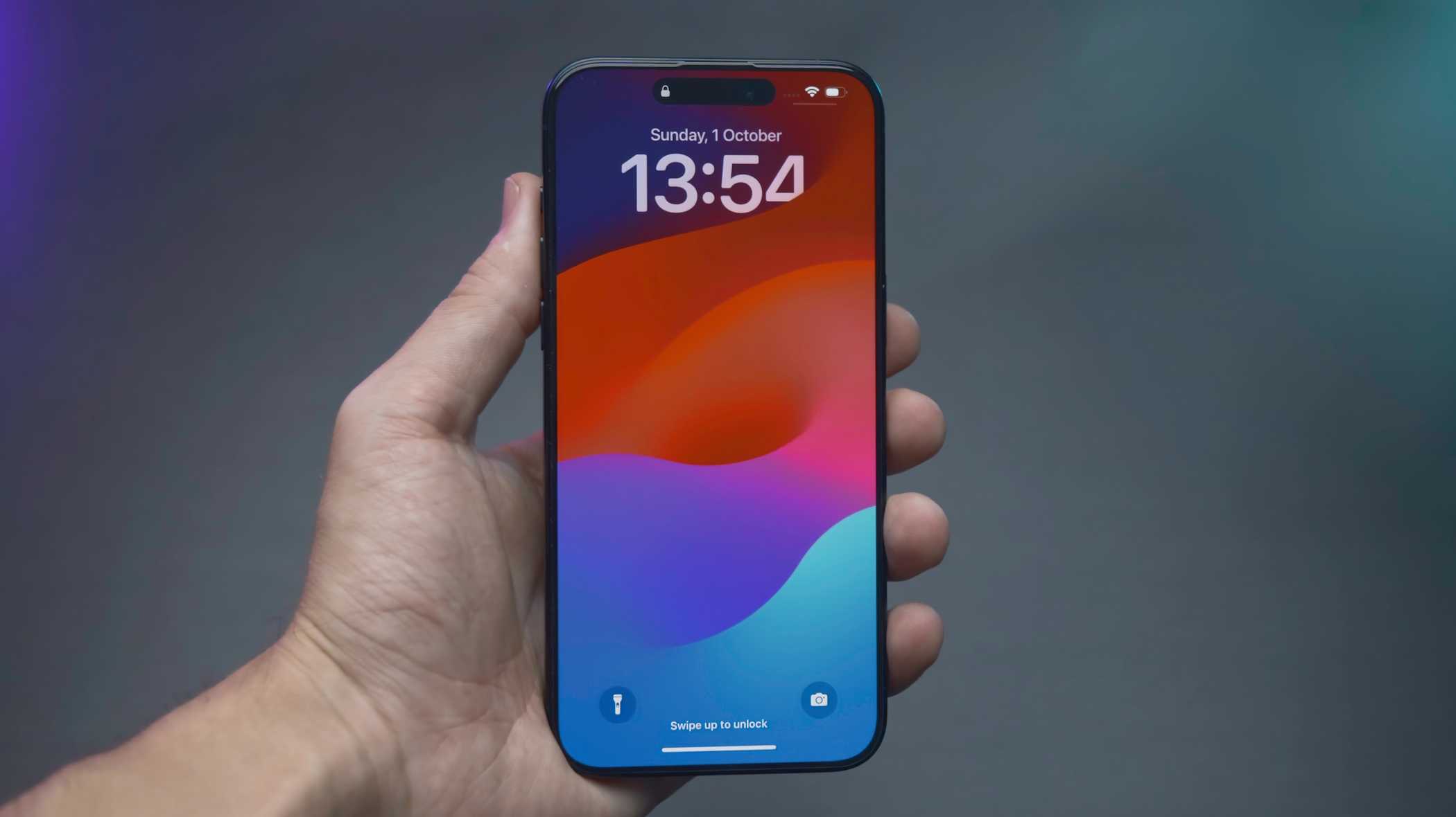 Человек держит iPhone 14 Pro с отображением времени