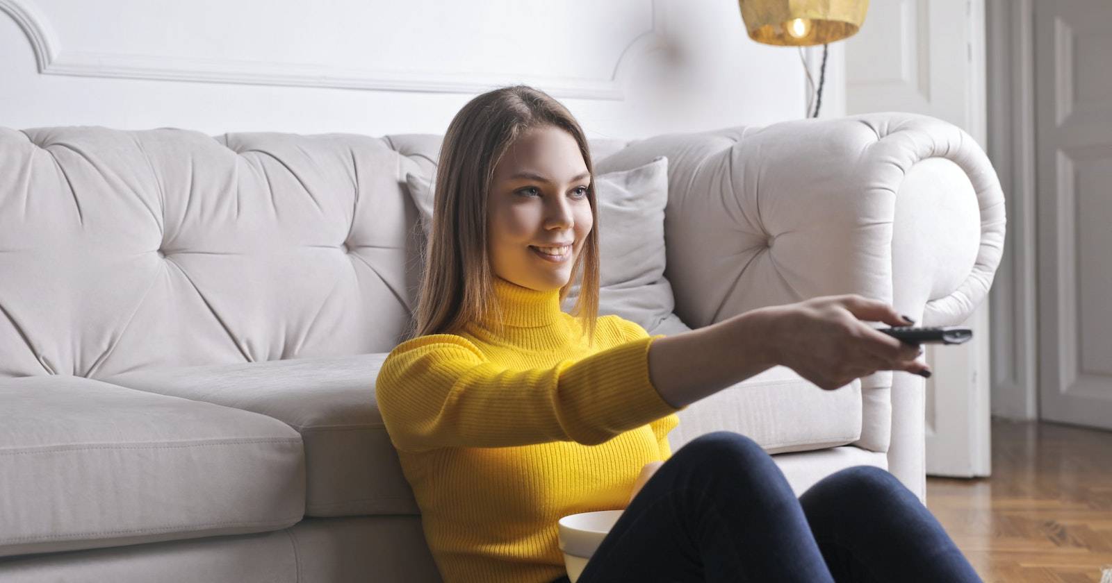 Женщина смотрит телевизор, держа в руках пульт дистанционного управления