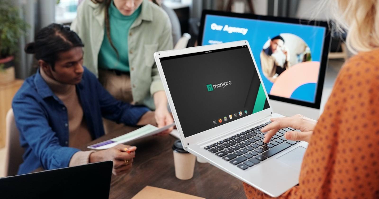 Женщина держит ноутбук с рабочим столом Manjaro