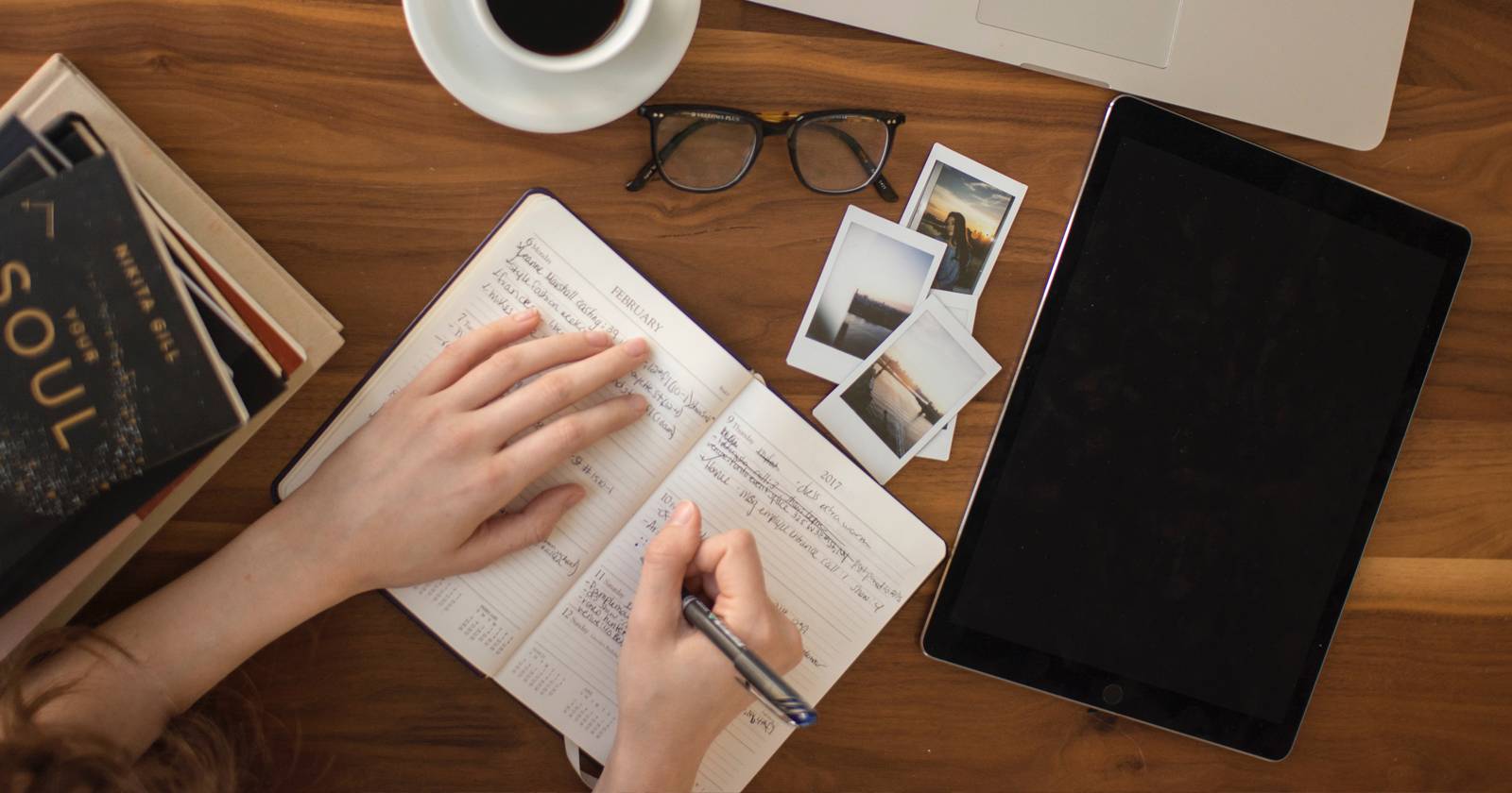 человек пишет в блокноте рядом с ноутбуком и планшетом