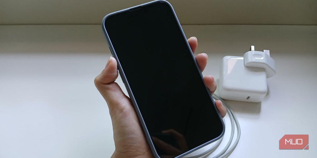 Рука держит iPhone с чёрным экраном