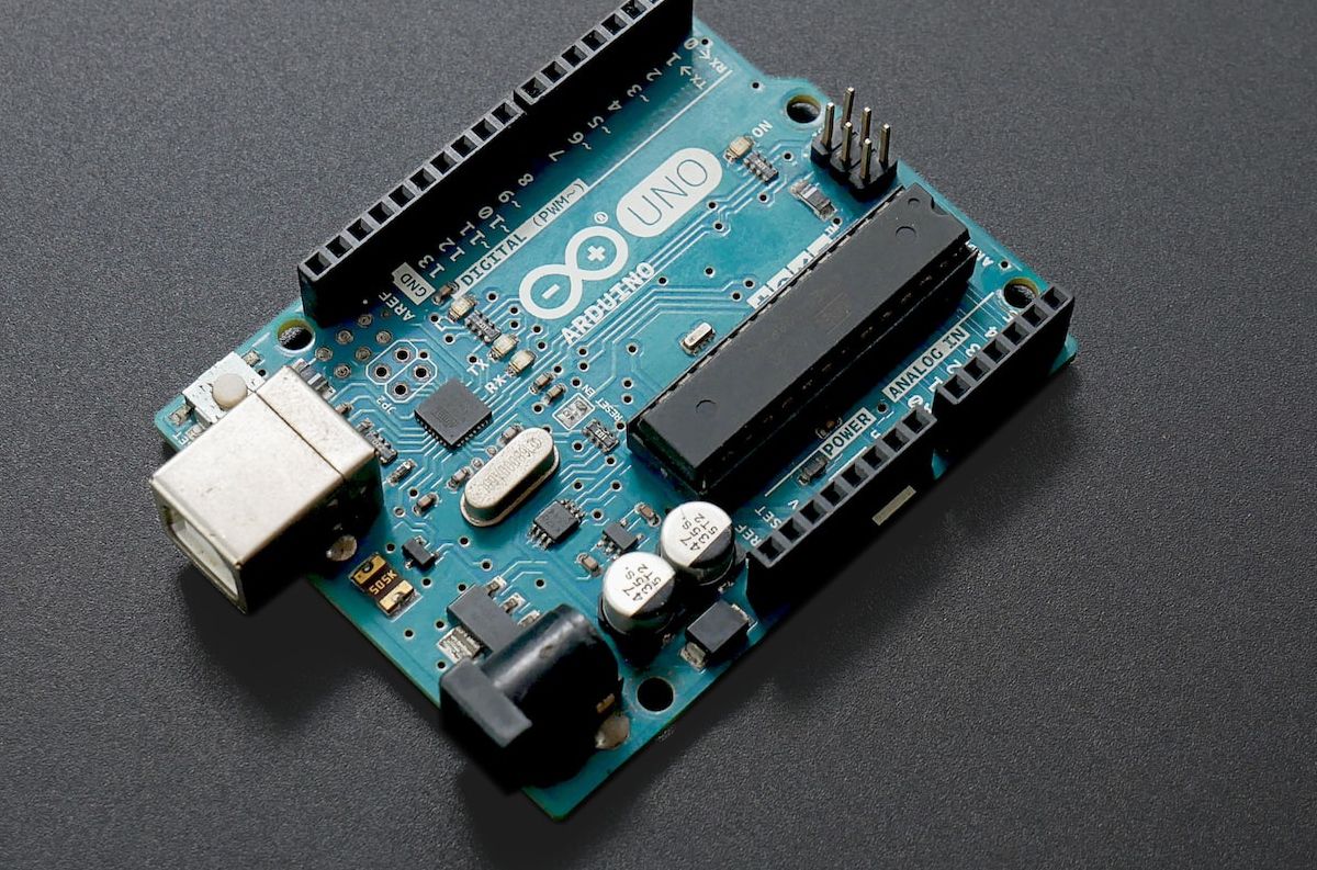Плата Arduino Uno на чёрной поверхности
