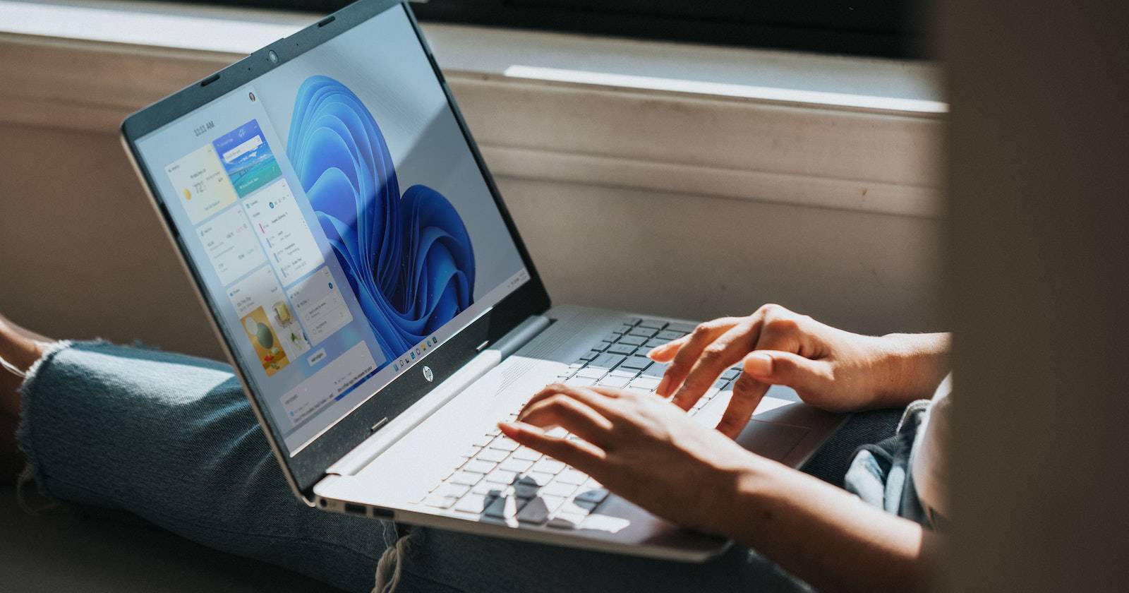 человек листает на ноутбуке с Windows, расположенном на коленях