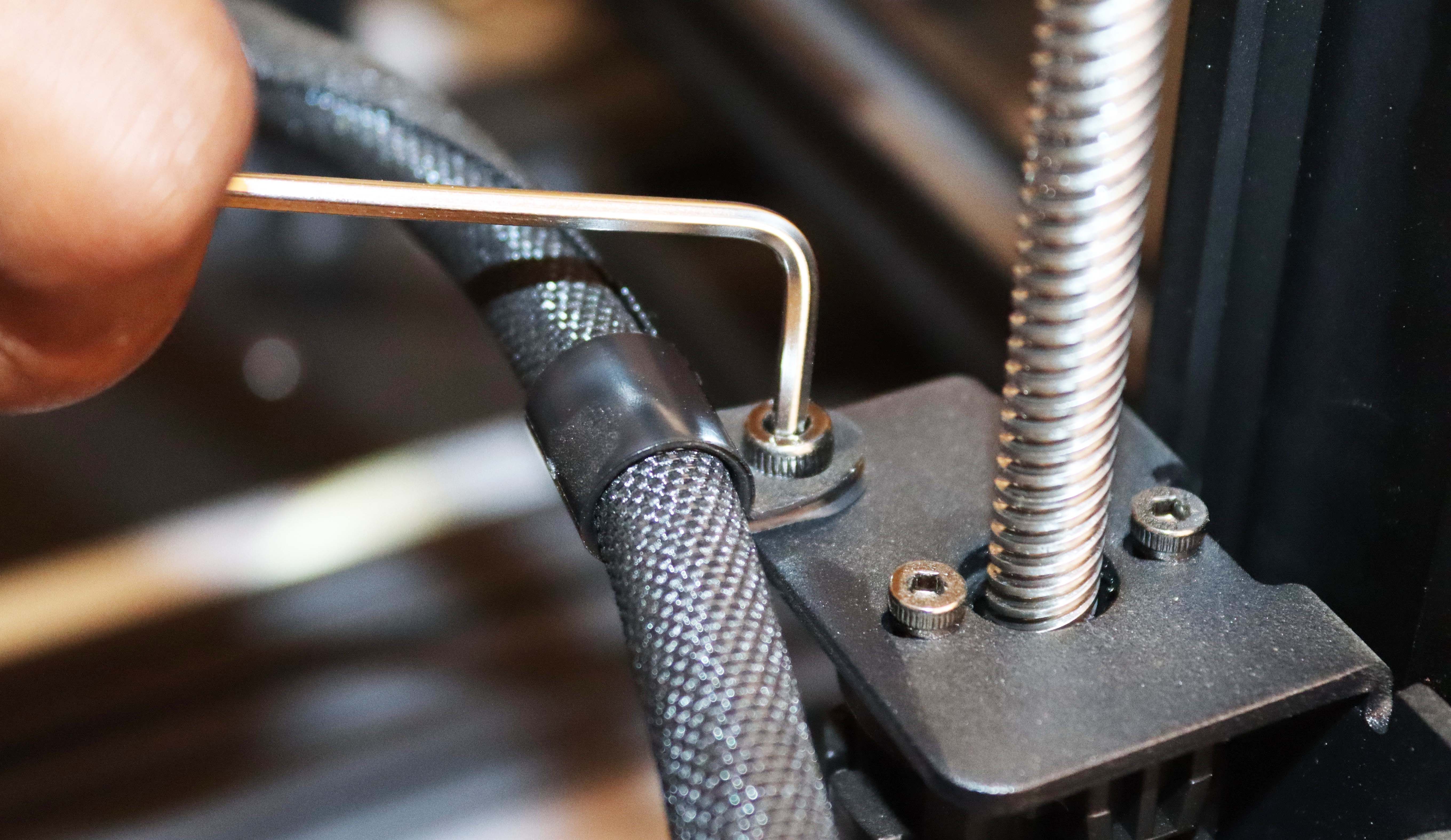 Using a wrench to tighten the screws on the print head harness