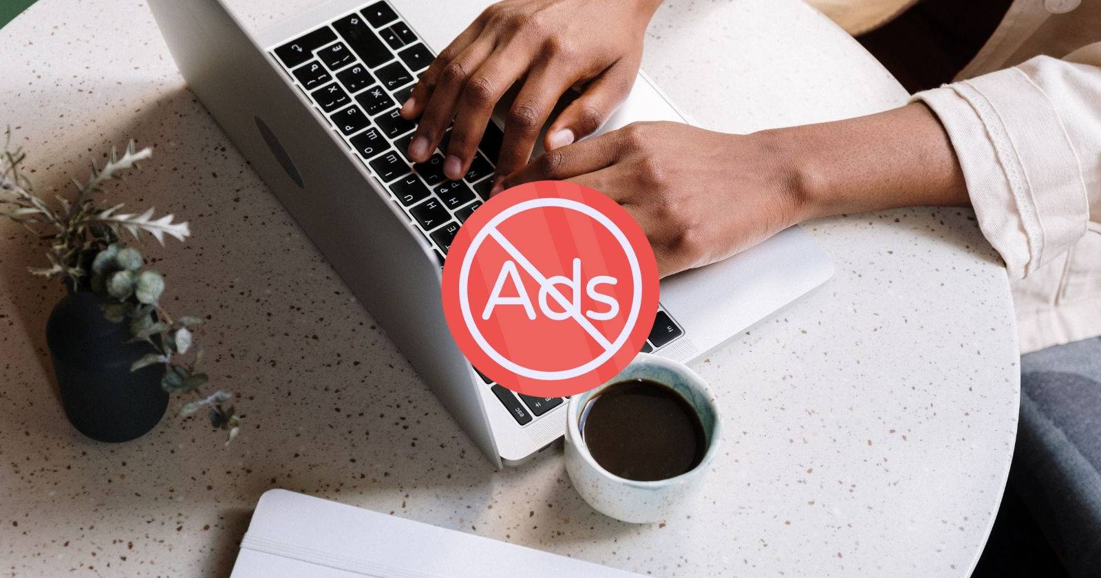 Пользователь за ноутбуком с иконкой блокировки рекламы в центре экрана