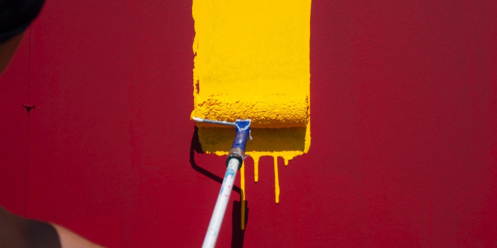 маляр с жёлким валиком наносит краску