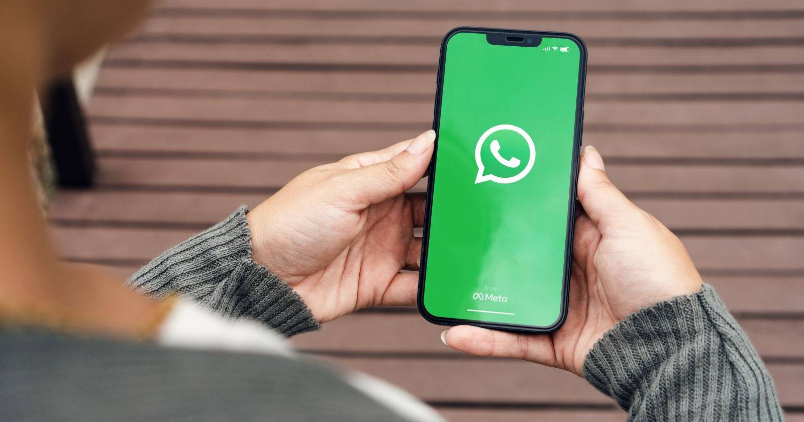 Девушка держит смартфон с приложением WhatsApp на экране