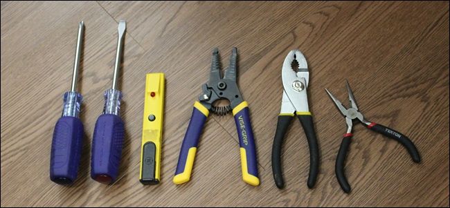 Набор инструментов: пассатижи, отвертки и индикатор напряжения на рабочем столе