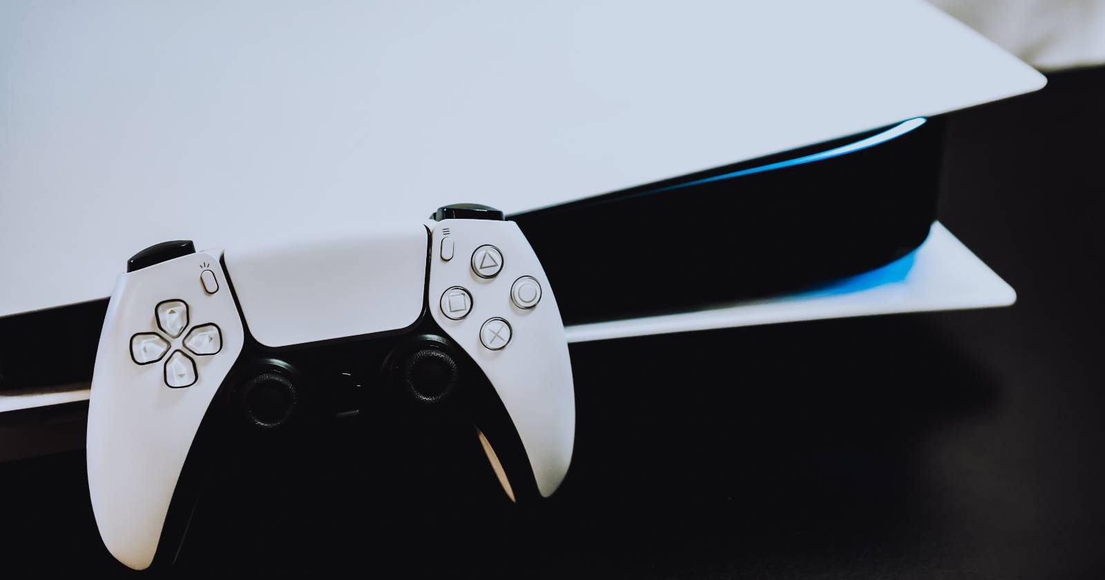 Белая консоль PS5 и белый контроллер PS5, опирающийся на консоль