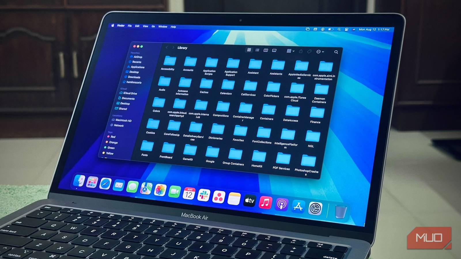 MacBook Air на столе, экран показывает папку Library