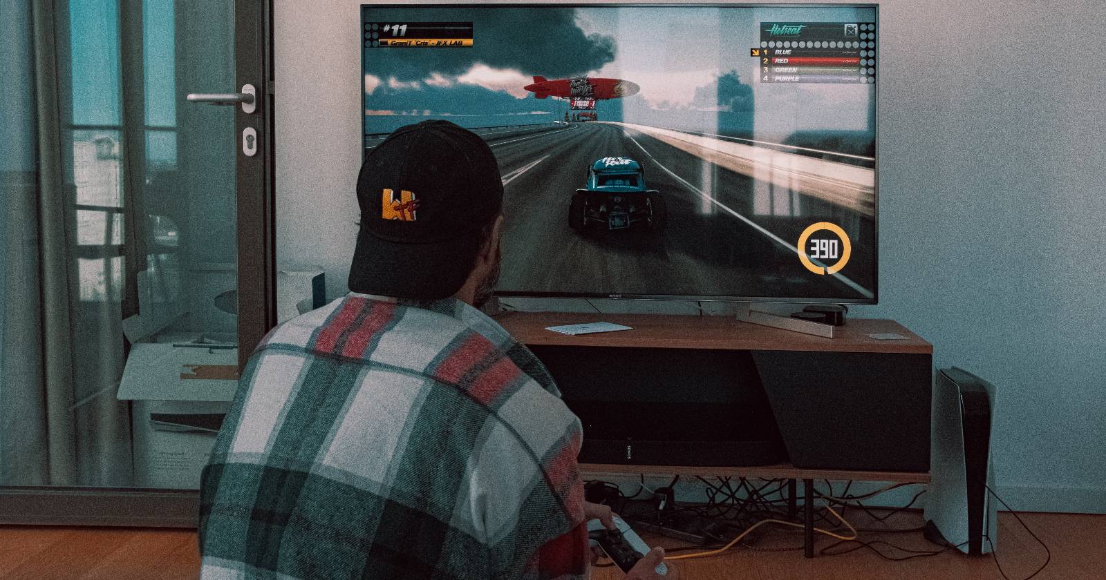 мужчина играет на приставке PS5, телевизор на заднем плане