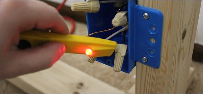 Фотография проводов в коробке с индикатором напряжения рядом для поиска фазы