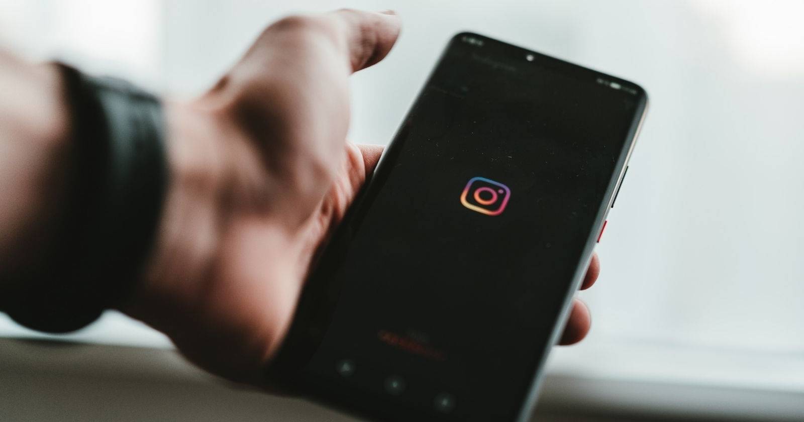 Человек держит телефон и использует Instagram