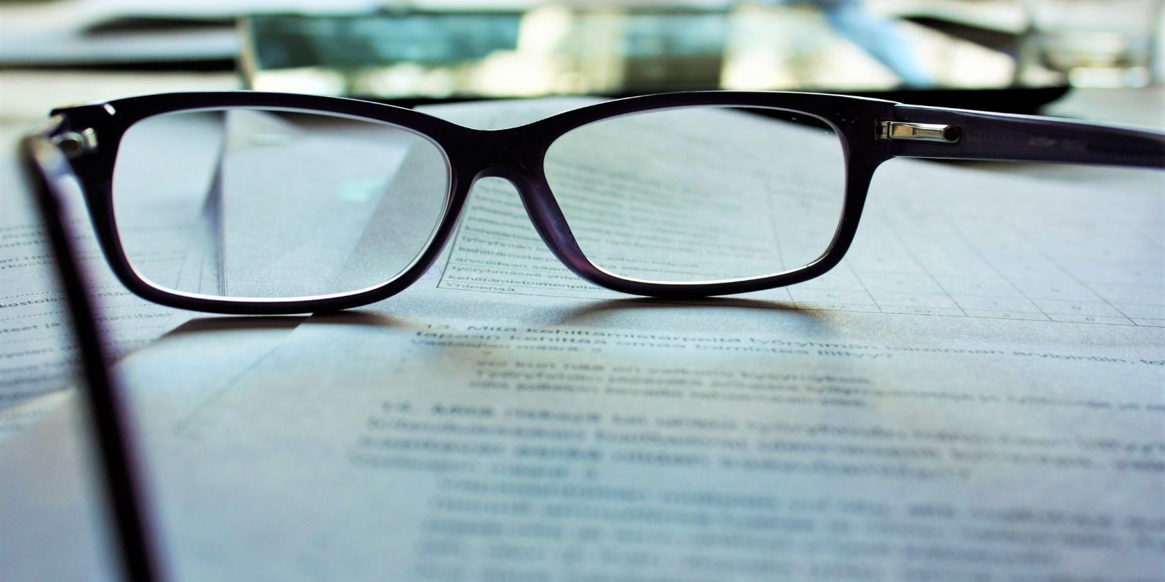 Чёрные очки в рамке на бумаге с печатным текстом