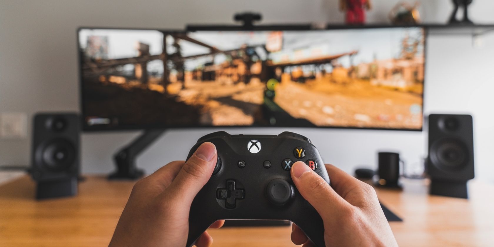 Человек держит беспроводной контроллер Xbox перед монитором