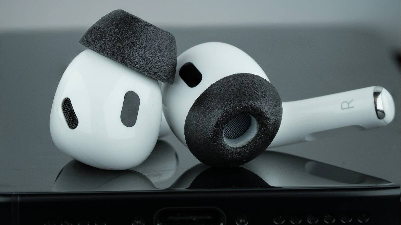 Насадки Comply из поролона на AirPods Pro, лежащие на iPhone.