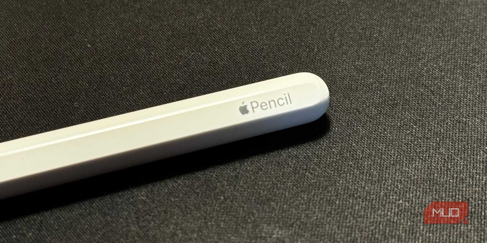 Apple Pencil второго поколения на чёрной поверхности, видно логотип Apple