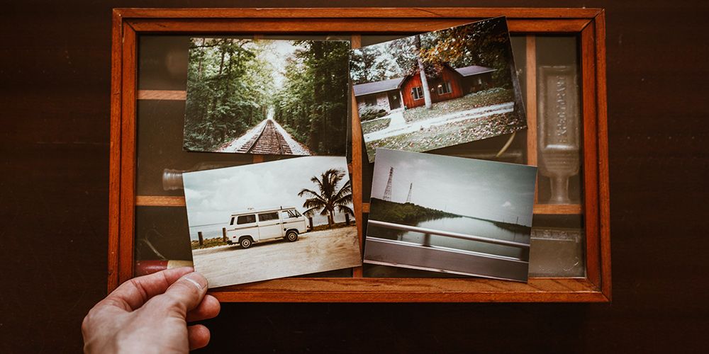 Рука держит фотографию на фоне рабочего стола