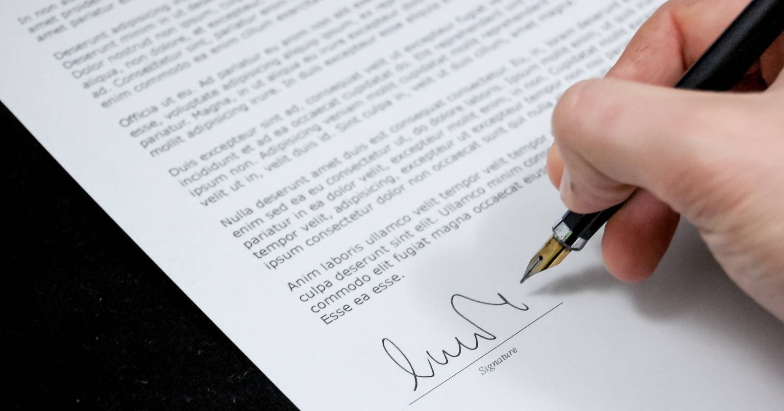 Человек подписывает юридический документ