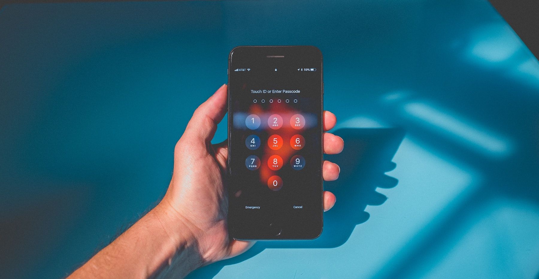 Рука держит iPhone с экраном ввода кода блокировки