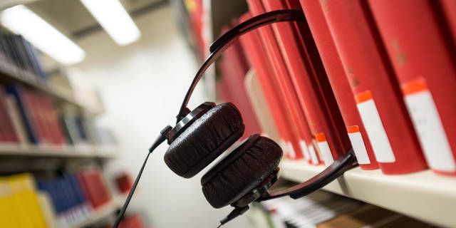 Наушники лежат на столе рядом с учебными материалами