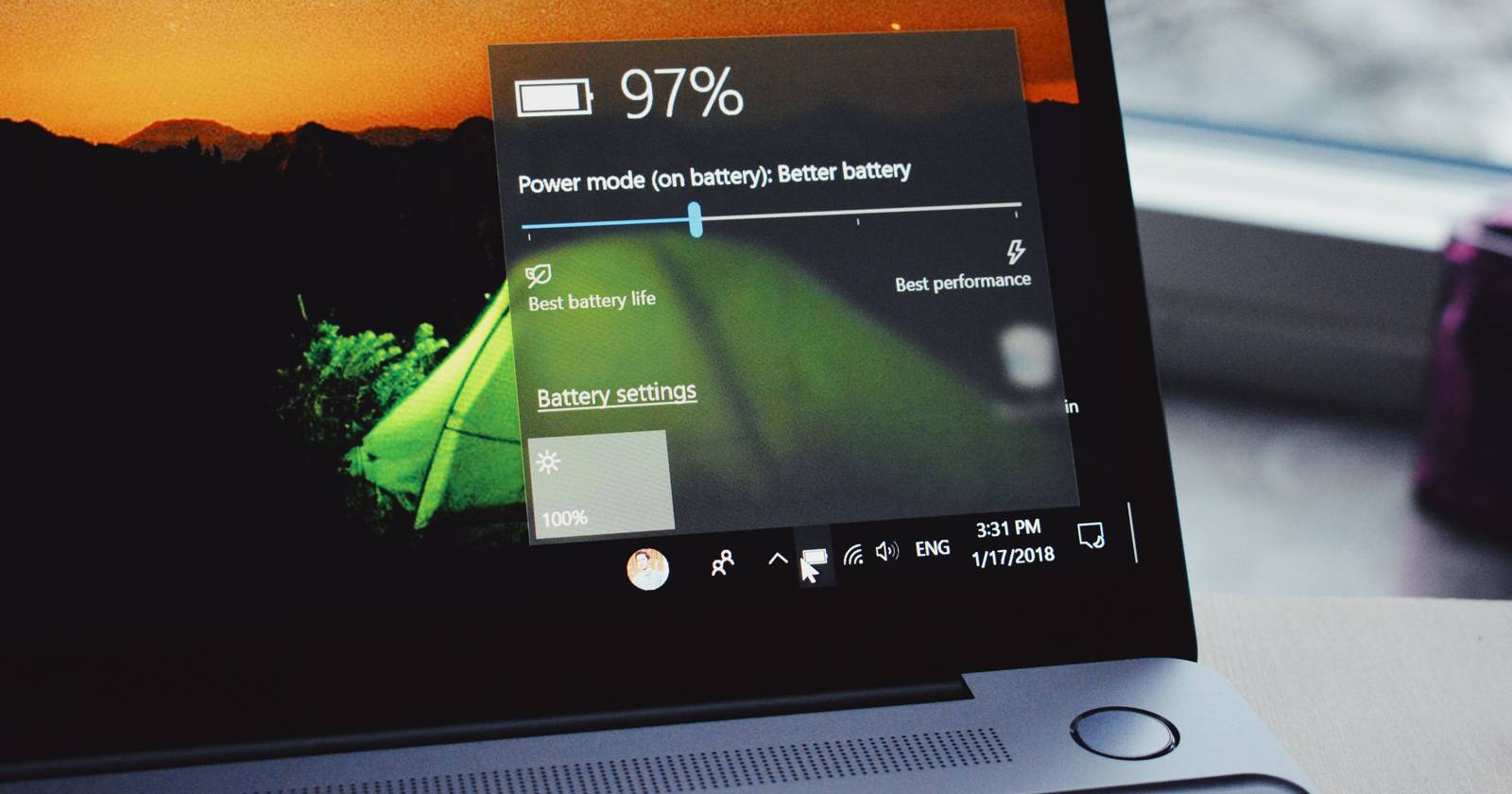 Ноутбук с Windows 10 на столе, на экране отображается процент заряда батареи.