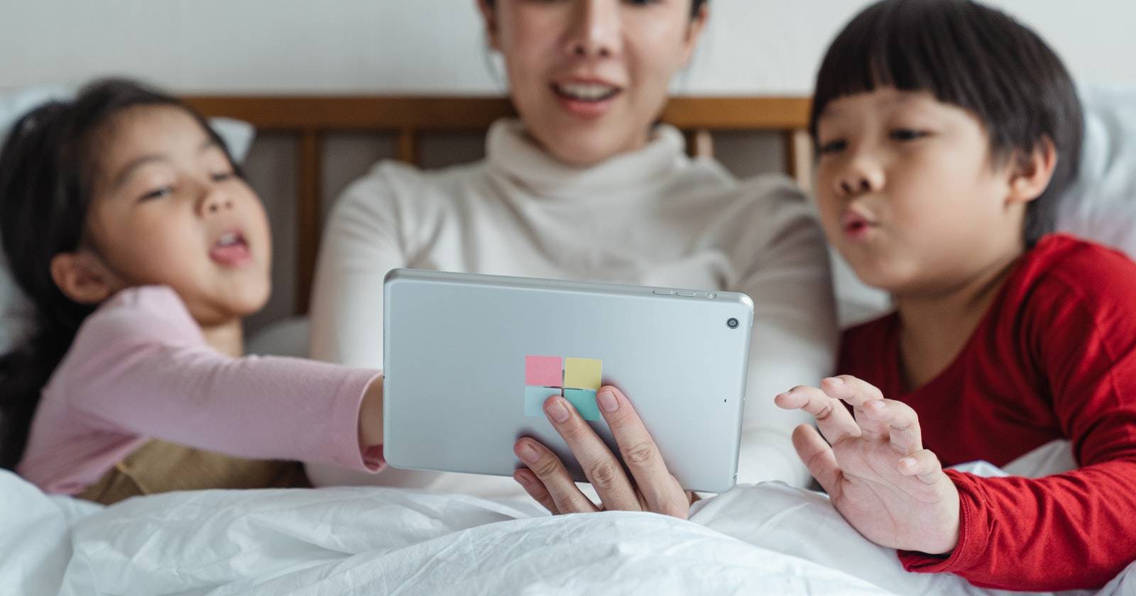 мать и двое детей с планшетом в кровати