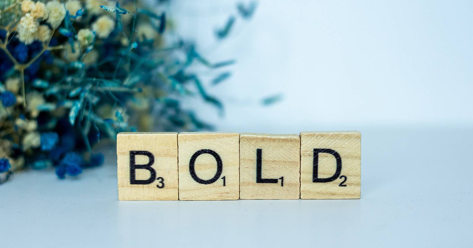 Слово «Bold» из букв игры Scrabble на фоне рабочего стола.