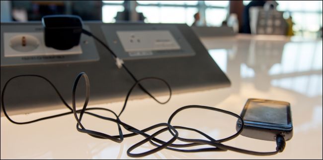 Смартфон подключённый к сетевому адаптеру, вставленному в стенную розетку