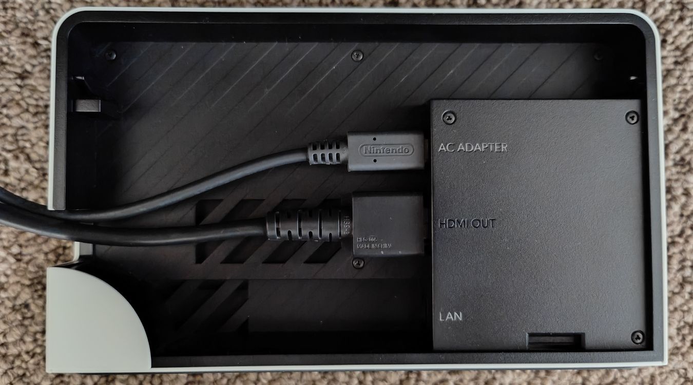 A photograph of a Nintendo Switch OLED Dock with the AC Adapter and HDMI ports plugged in