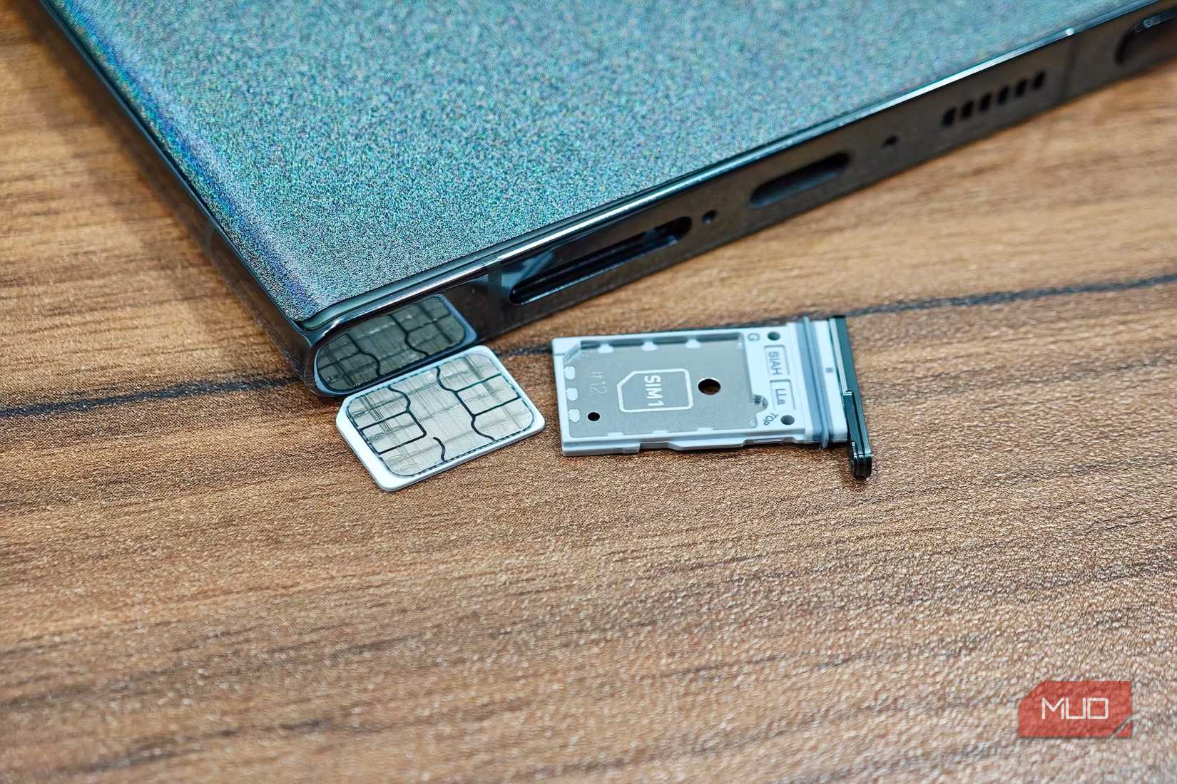 Телефон Samsung лежит экраном вниз, рядом nano SIM и слот для SIM-карты.