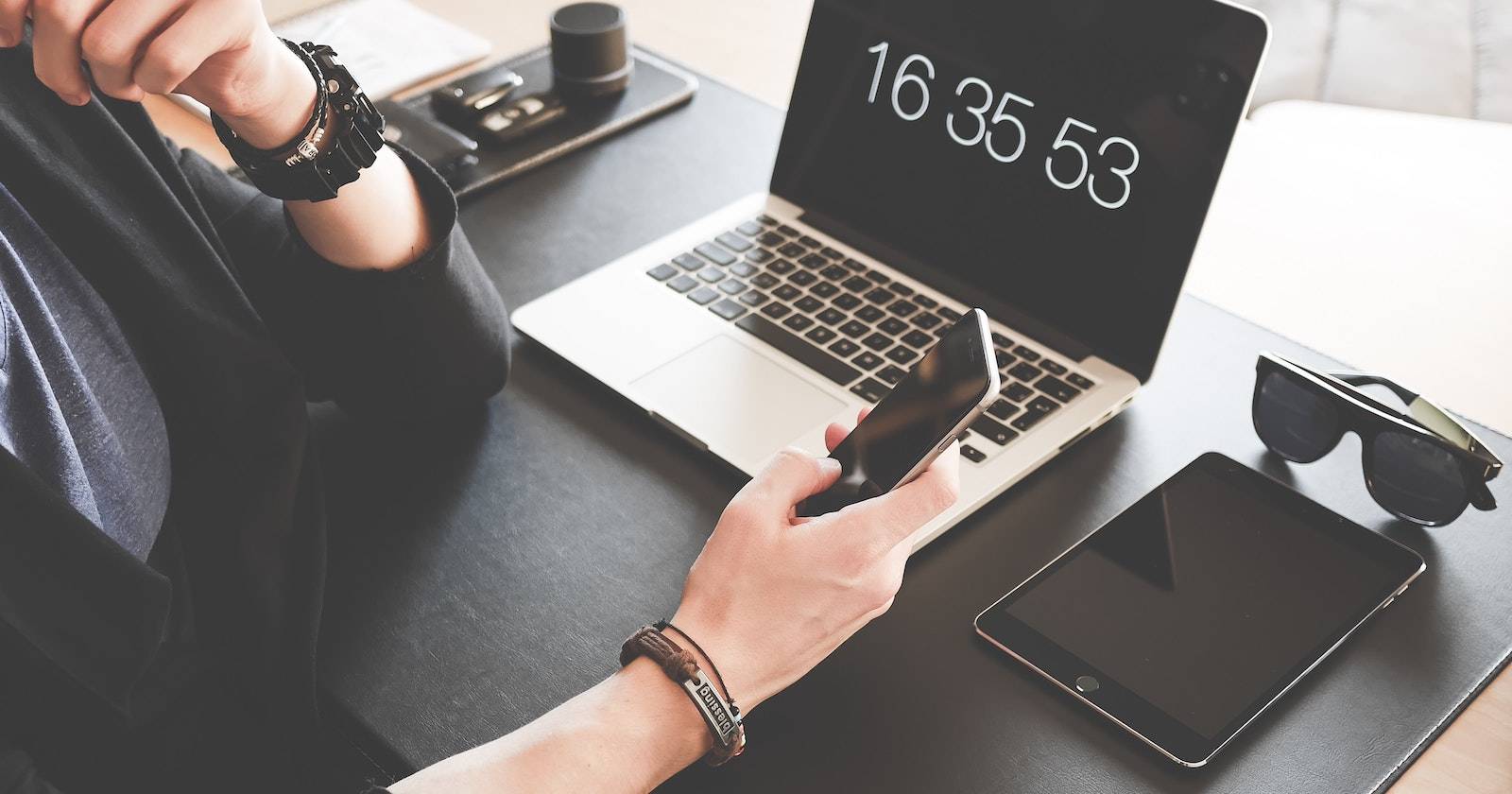 Человек использует iPhone рядом с iPad и MacBook на столе