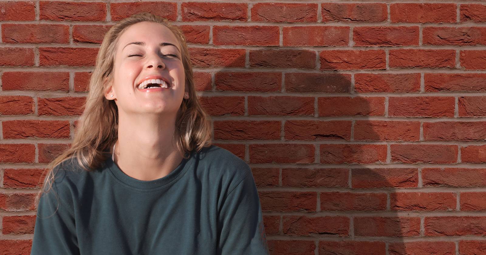 Женщина перед кирпичной стеной с заметной тенью