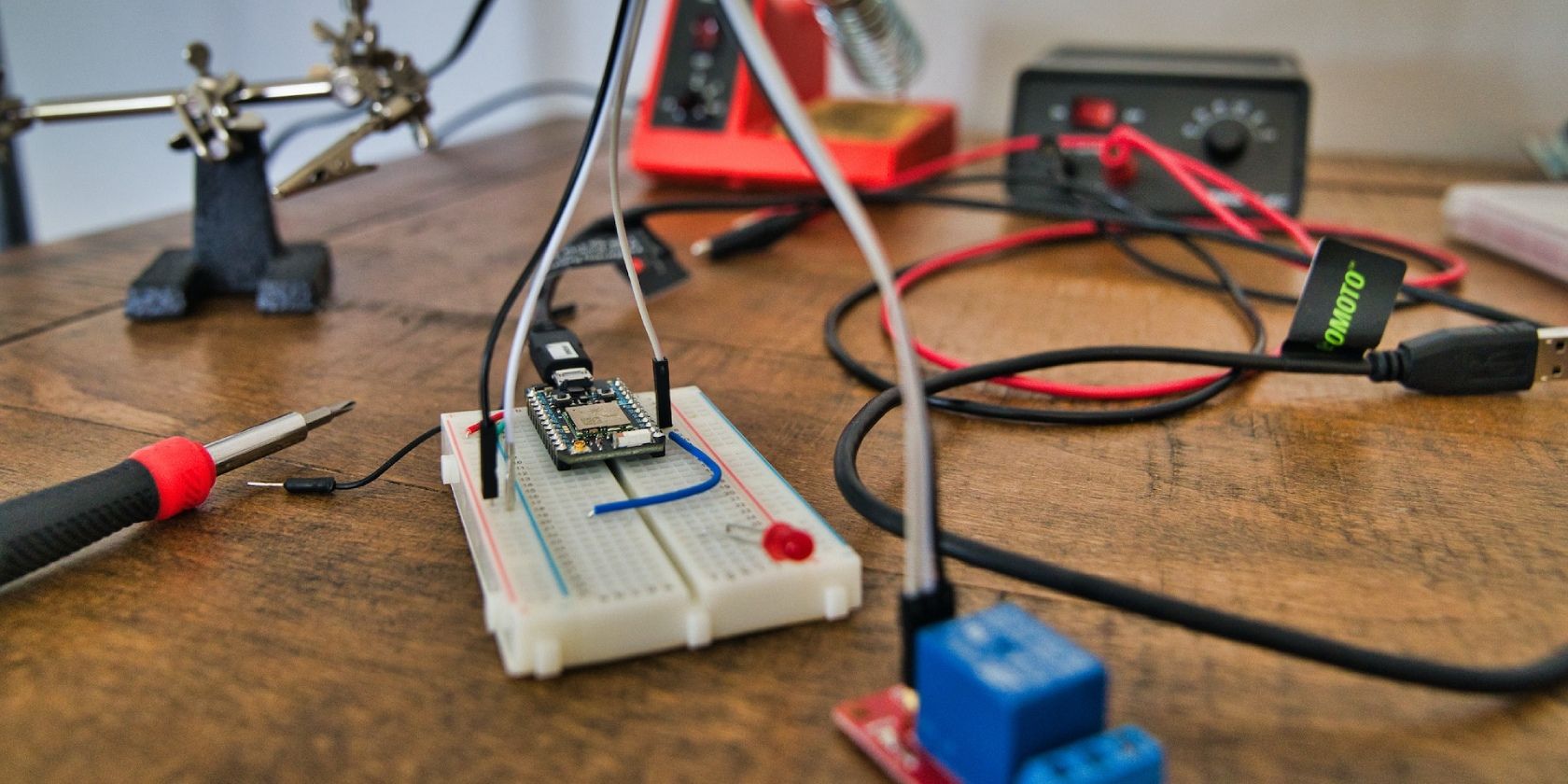Breadboard project with relay module on a table with a solder gun and other components