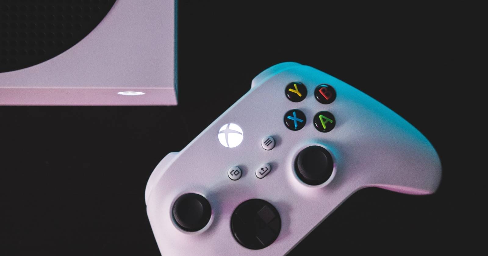 Белый геймпад Xbox Series S рядом с консолью Xbox Series X на чёрной поверхности