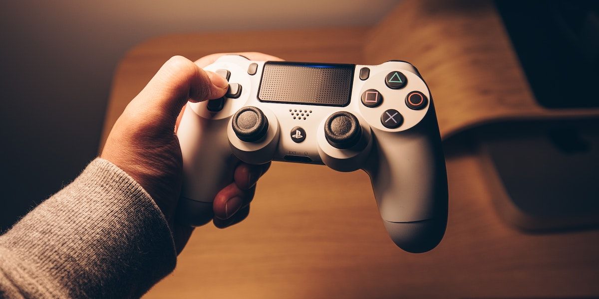Рука держит белый контроллер PS4 — подготовка аксессуаров