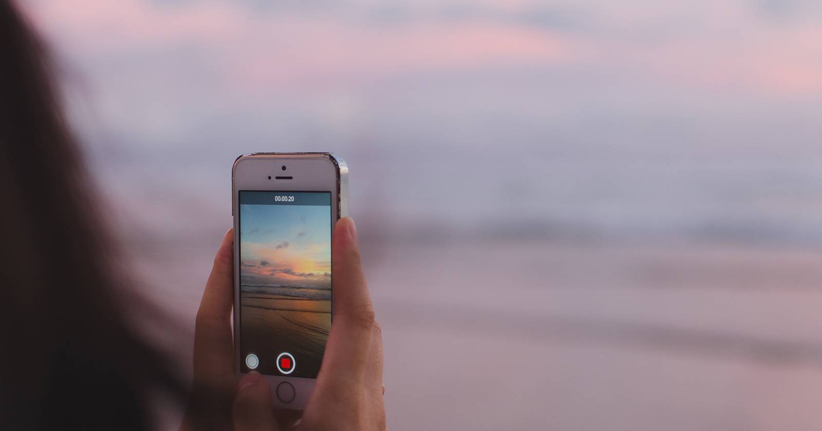 Женщина фотографирует закат над океаном