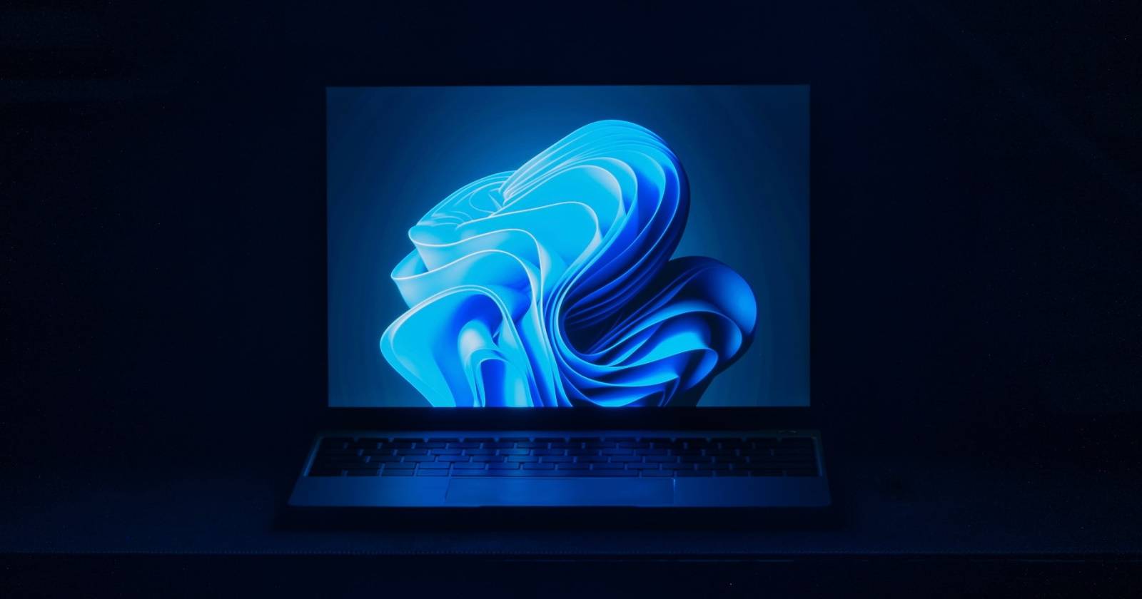 Ноутбук с Windows 11 в тёмной комнате