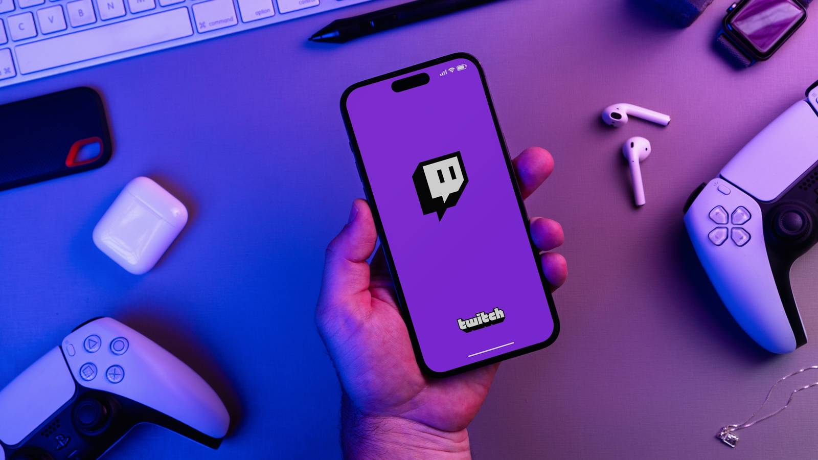 Человек держит смартфон с логотипом Twitch на экране