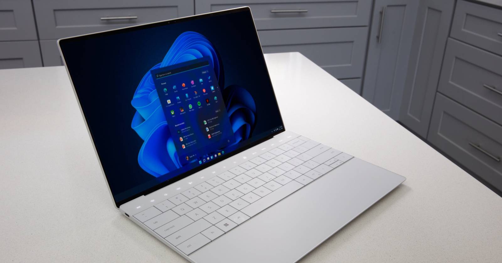 Ноутбук стоит на белом столе.