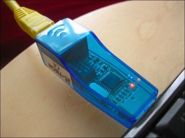 USB Ethernet адаптер рядом с ноутбуком и кабелем