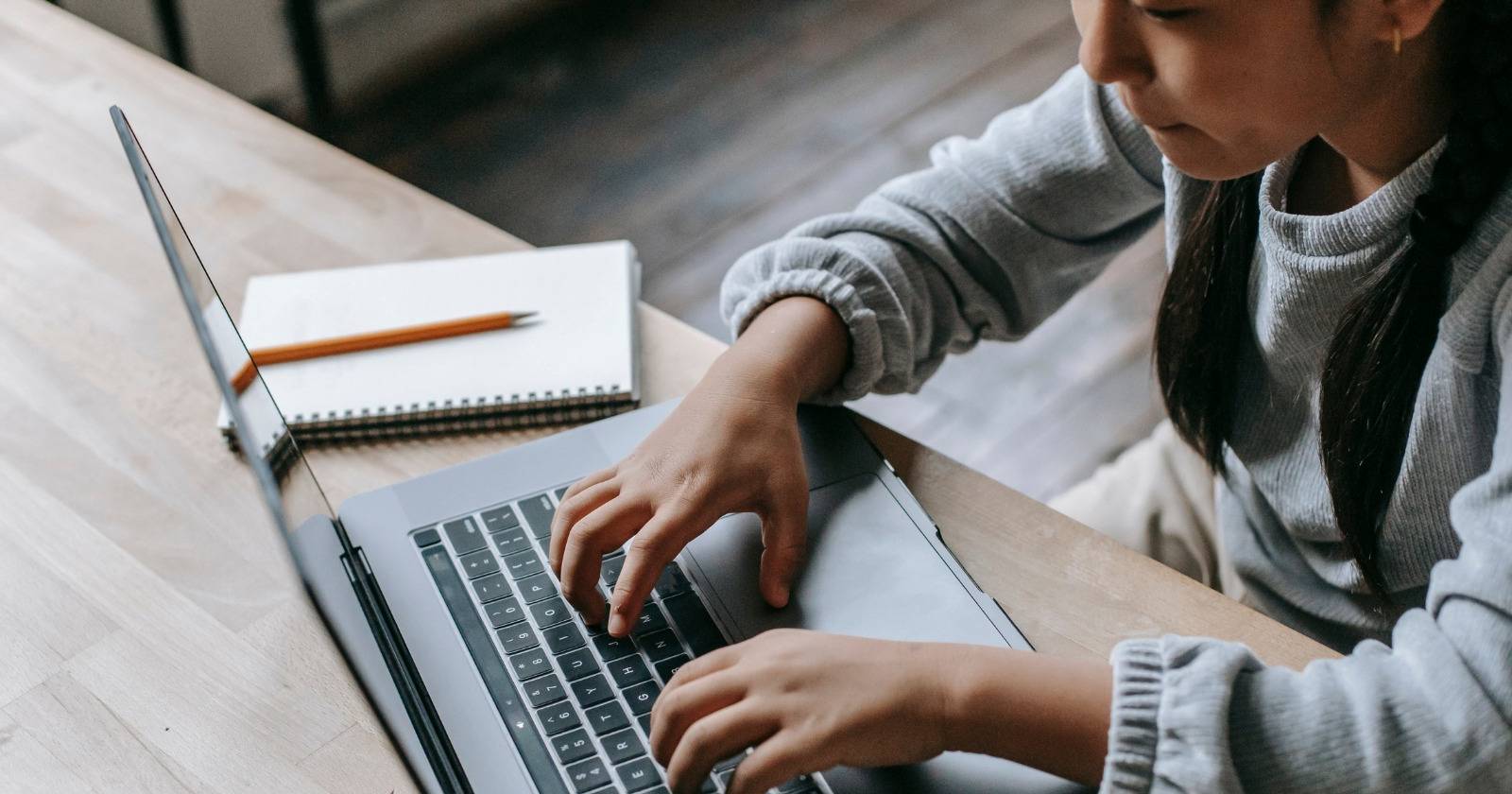 Ребёнок сидит за столом с ноутбуком