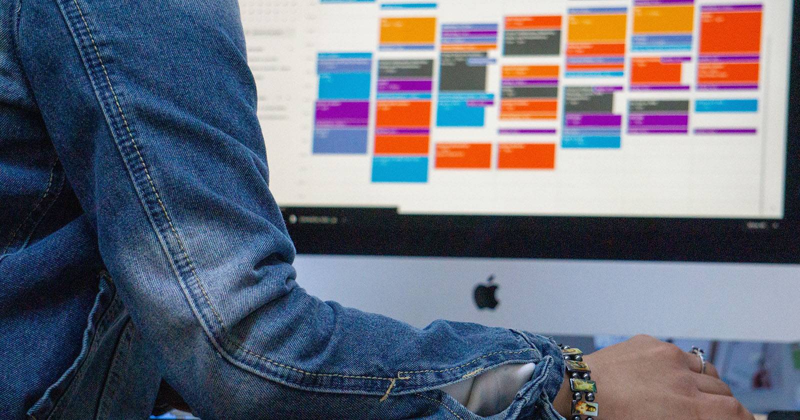 Человек работает за компьютером с календарём на экране