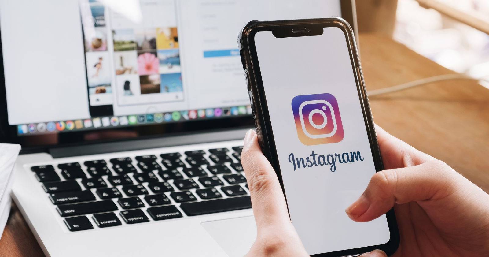 логотип Instagram на смартфоне на фоне ноутбука