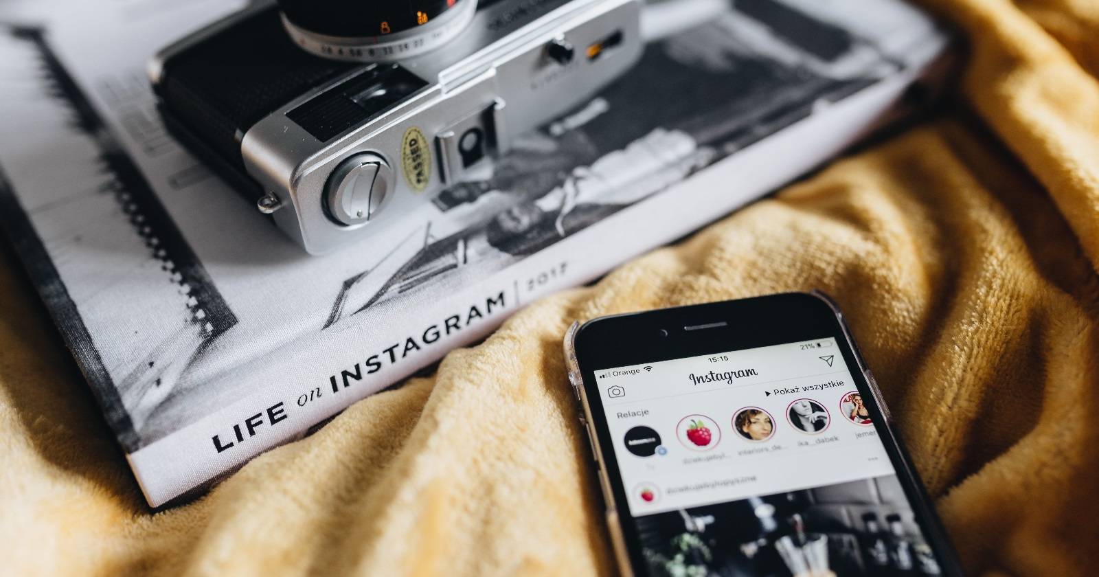 Смартфон с открытым Instagram рядом с книгой и камерой
