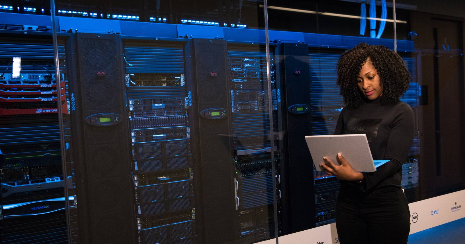 Женщина работает на ноутбуке на фоне компьютерных стоек