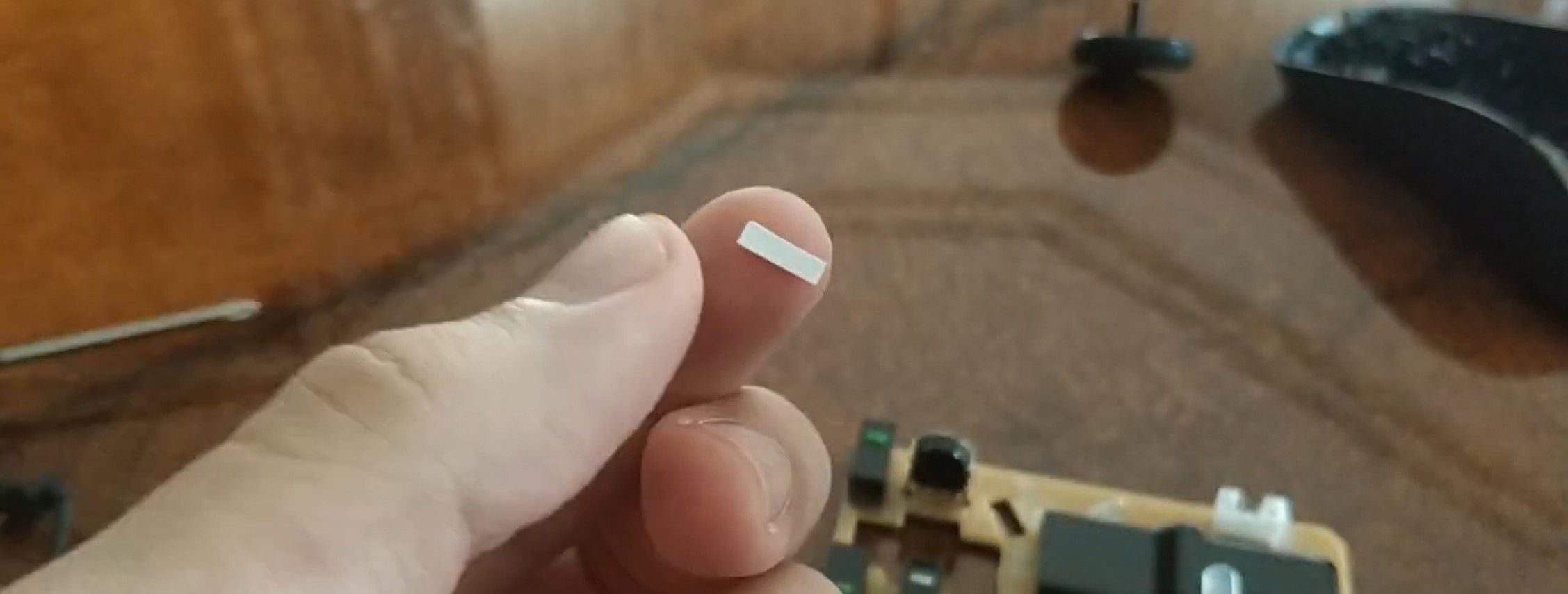 Мужчина держит кусочек бумаги, чтобы подложить под втулку колесика мыши