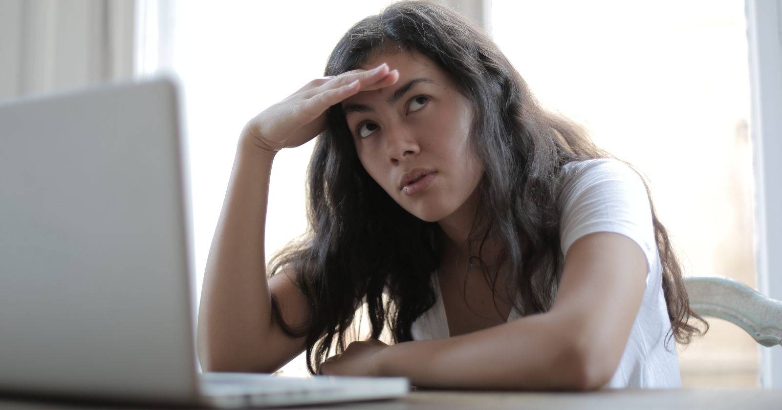 женщина с открытым ноутбуком задумчиво смотрит