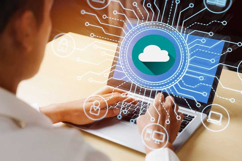 Person using a laptop with cloud computing illustrations appended on top